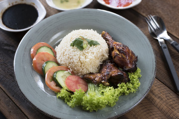Popular Malaysian dish Nasi Ayam or chicken rice with baked chicken pieces, tomato, cucumber, salad, soup, soy sauce and chili sauce.