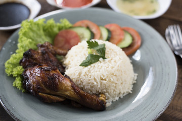 Popular Malaysian dish Nasi Ayam or chicken rice with baked chicken pieces, tomato, cucumber, salad, soup, soy sauce and chili sauce.