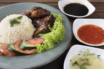 Popular Malaysian dish Nasi Ayam or chicken rice with baked chicken pieces, tomato, cucumber, salad, soup, soy sauce and chili sauce.