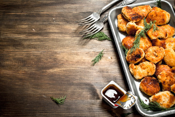 Chicken nuggets on a steel tray with sauce.