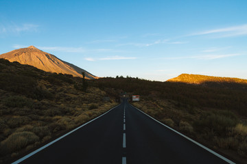 Road with sunrise light on volcanic hills in desert landscape
