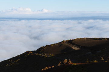 Empty road above cloud inversion in desert landscape while sunrise