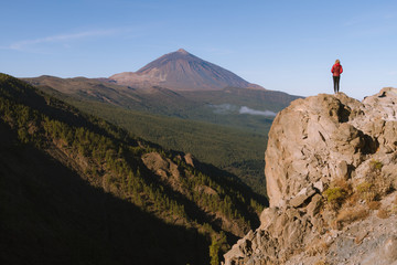 Woman standing on the cliff with volcano in the background