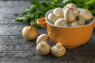 Fresh mushrooms in a yellow bowl on a rustic wooden table. Vegetarian food is on the table.