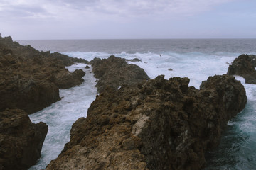 Fototapeta na wymiar Breaking waves on coastline in dark cloudy weather