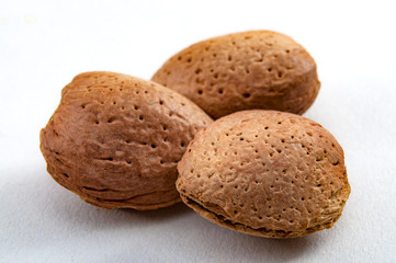 Natural healthy foods, organic nuts and vegan diet concept with close up on a bunch almonds still in shell isolated on white background
