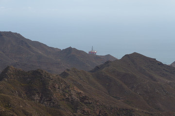 Houses on hillside of green mountain covered in fog