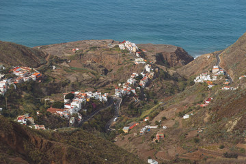 Remote road and village on coastline next to the beach with crashing waves