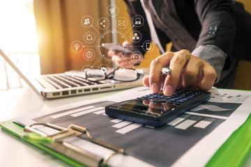 Fototapeta premium businessman hand working with finances about cost and calculator and laPtop with tablet and smartphone on withe desk in modern office in morning light 