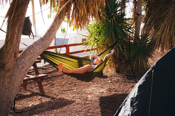 Young woman with tattoo sleeping in hammock in campsite
