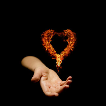 Hand holding a burning flame in the shape of a heart.