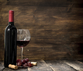 Red wine with a branch of grapes and a corkscrew.