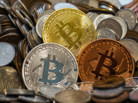 Gold, Silver and Bronze Bitcoin coins on large stack of coins