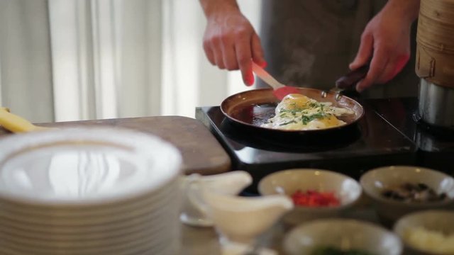 Male chef in the restaurant cooks eggs