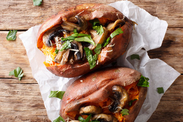 Baked whole sweet potato with mushrooms and cheese close-up. horizontal top view
