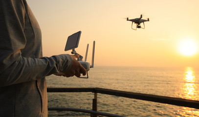 Fototapeta premium silhouette of remote control a flying drone which taking photo over sunrise sea