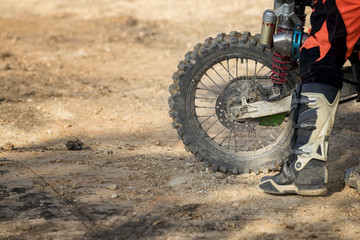 Close-up of dirty wheel of motocross bike with racer