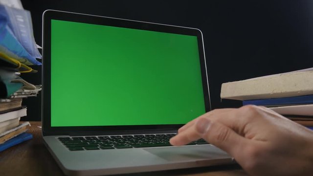 Close up of man works at laptop late ot office with Green Screen. Businessman working at night at the computer with Choma Key.