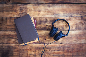 Concept Audiobook. Headphones and a Pile of Books on a Wooden Background