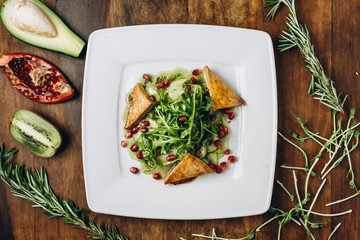 Kiwi carpaccio with tofu cheese, lettuce, arugula, cucumber and pomegranate grains, with herbs, on...