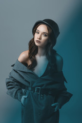sensual model posing in autumn coat and military helmet, isolated on grey with blue filter