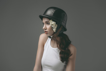 beautiful young girl in military helmet with white roses, isolated on grey