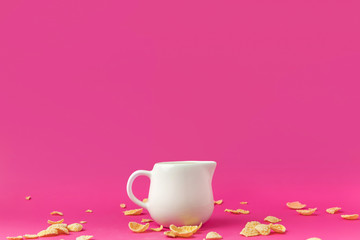 Fototapeta na wymiar close-up view of jug with milk and crunchy corn flakes on pink