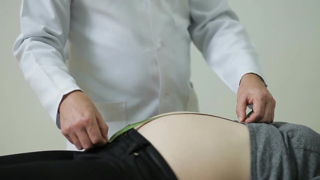 Doctor measures the belly of a pregnant woman