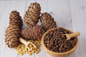 Peeled and unrefined pine nuts and cedar cones on a wooden table