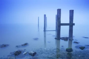 Gordijnen Jetty in the sea on a foggy morning at dawn © sara_winter