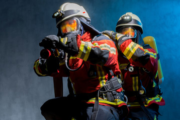 Feuerwehrtrupp bei der Brandbekämpfung mit PA, Flammen spiegeln sich in Atemschutzmasken