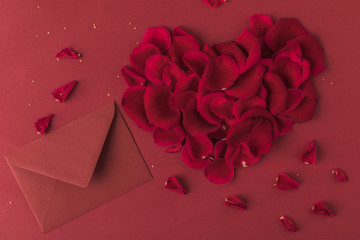 top view of heart made of roses petals and envelope isolated on red, st valentines day concept