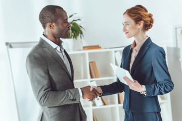 african american businessman and caucasian businesswoman shaking hands