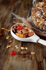 Granola in a glass jar and wooden spoon. Healthy nutrition concept. Rustic style