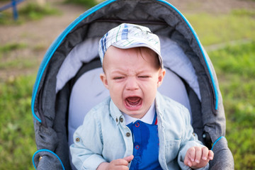 Little boy cries in a stroller