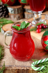 Hot cranberry tea in a glass jug surrounded by Christmas attributes