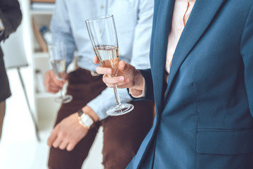 cropped image of men holding glasses in hands