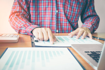 Business man hand with Financial charts and laptop on the table