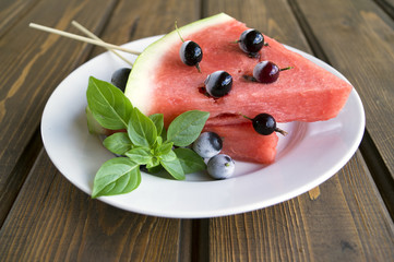 Summer fruit snack of watermelon and frozen berries. Watermelon slices on a stick.