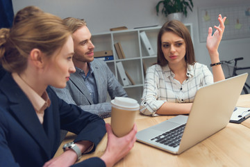business team have discussion while sitting at table with laptop
