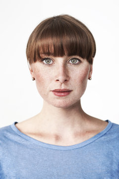 Biometric passport photo of a green-eyed read-haired woman with freckles and bangs