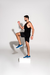 side view of sportive man doing step aerobics on block