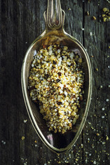 Spoon of lemon pepper on a wooden background