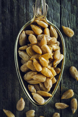 Spoon of peeled sunflower seeds on a wooden background