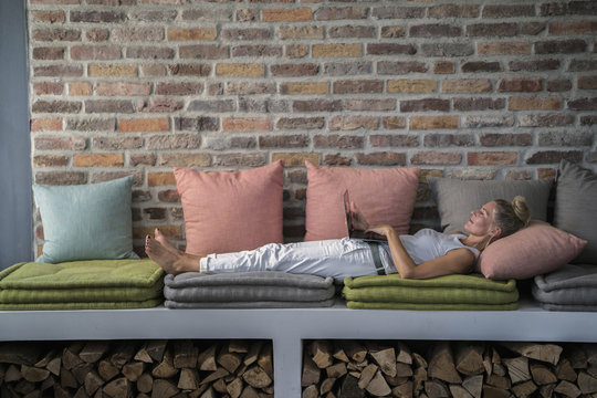 Mature woman lying on couch, using laptop