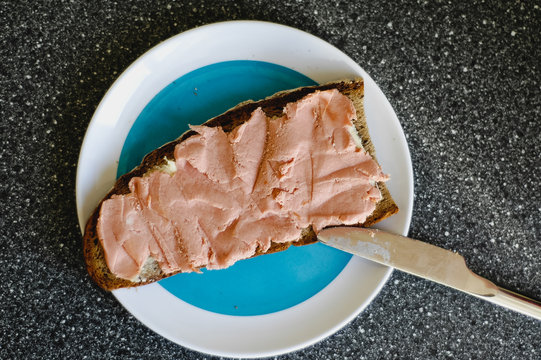 Slice of German dark farmhouse bread with butter and a savory tea sausage spread, so called Teewurst, a German pâté made of smoked bacon and pork meat, typical German breakfast or Brotzeit