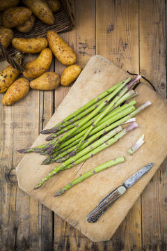 Green asparagus and pocket knife on wooden board