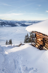 Schneebedeckte Hütte mit Blick ins nebelige Tal