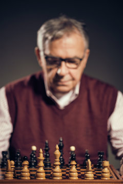 Portrait of senior man who is participating in chess game. 