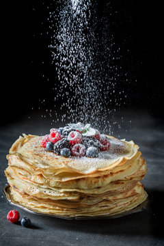 Falling powdered sugar on pancakes with berries